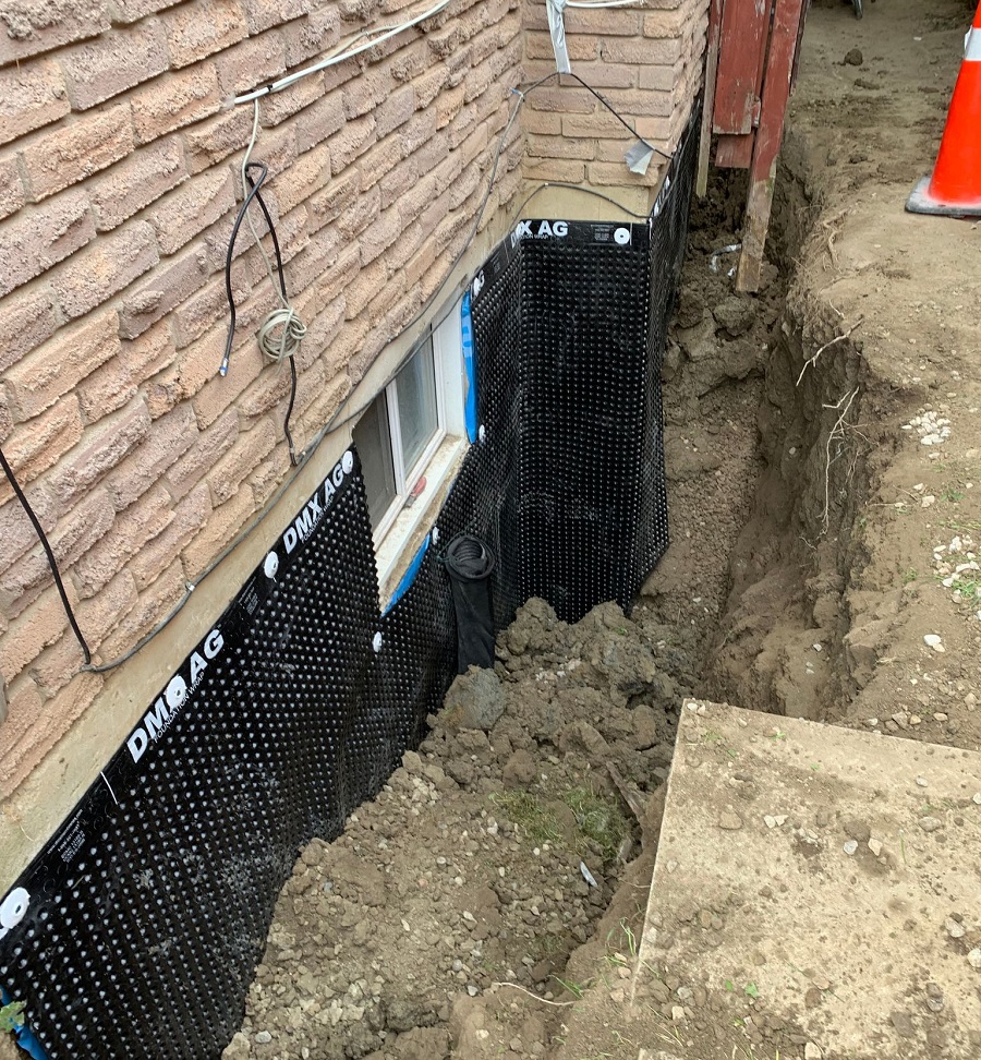 basement window with some digging work done around it, displaying GSI's waterproofing services
